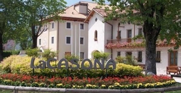 a building with a sign in front of a garden at Hotel Ristorante La Casona in Feltre