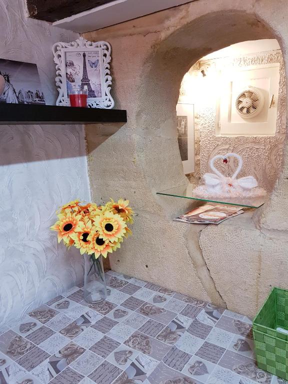 un vase de tournesols dans une pièce avec un mur dans l'établissement Appartement au coeur du Paris., à Paris