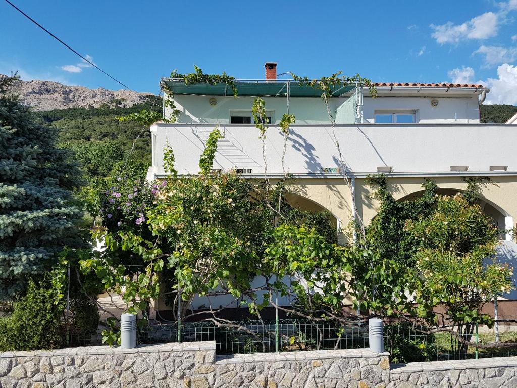 a white house with trees in front of a wall at Apartments Polic with Terrace in Baška