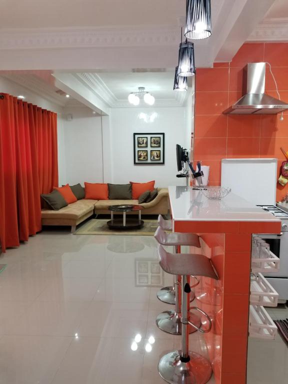 Appartement Confort Fann hock في داكار: مطبخ وغرفة معيشة بجدار احمر