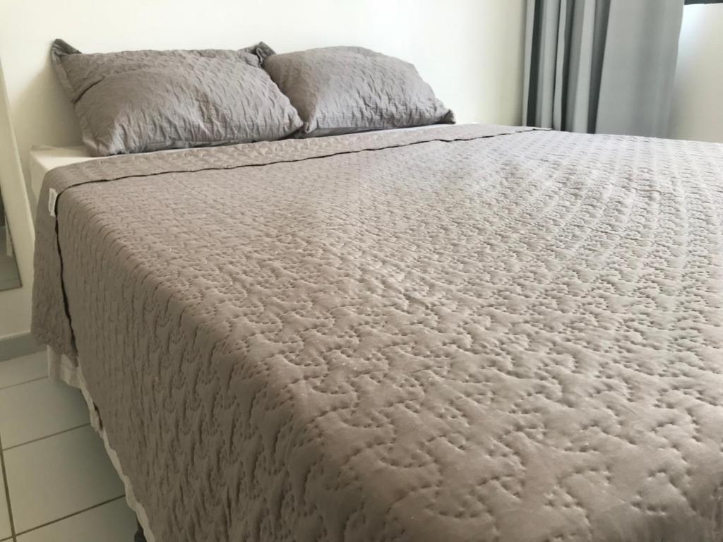 a bed with a white comforter and two pillows at Flat Parque Jaqueira Home Service in Recife