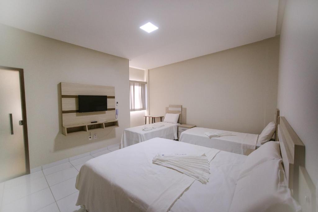 um quarto de hospital com duas camas e uma televisão em O Neves Hotel em Guanambi
