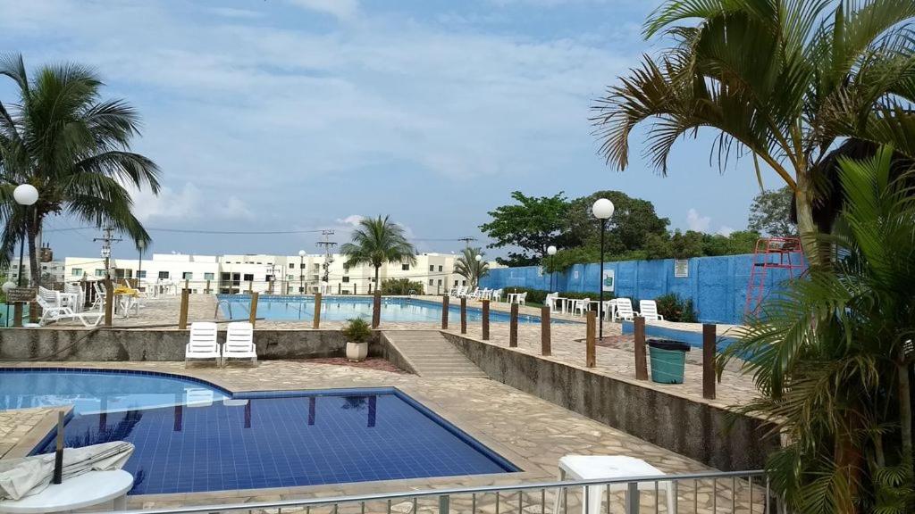 uma piscina de resort com cadeiras e palmeiras em Apartamento em Condomínio Marinas Clube em São Pedro da Aldeia