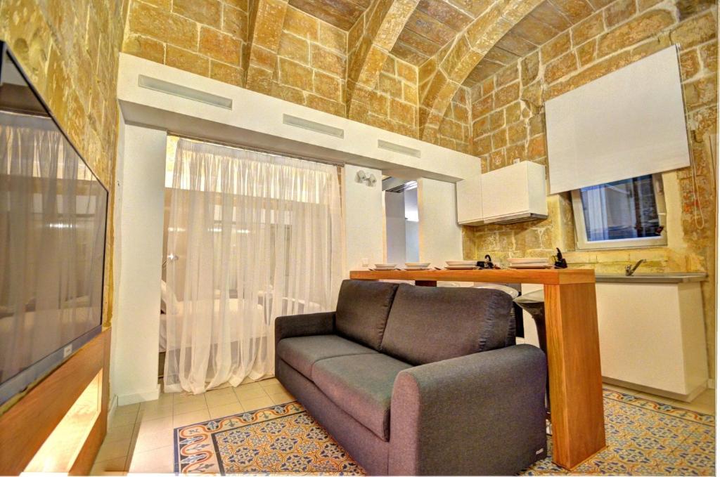ein Wohnzimmer mit einem Sofa und einem Tisch in der Unterkunft Coral Apartment (Valletta) in Valletta