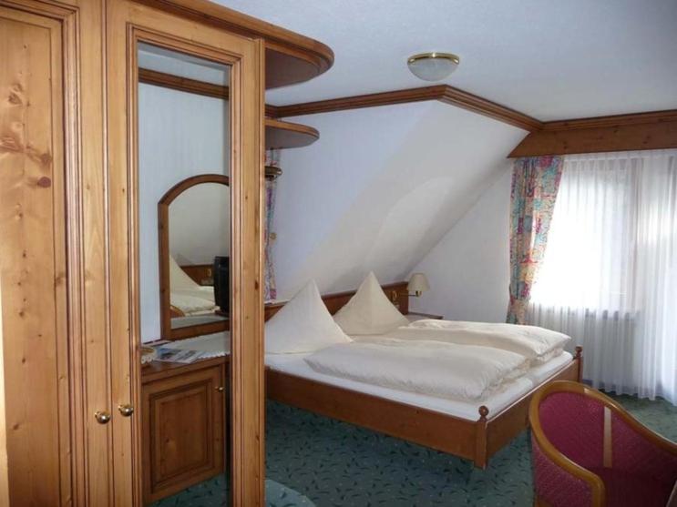 a bedroom with a bed and a large mirror at Decker's Bio Hotel zum Lamm in Baiersbronn