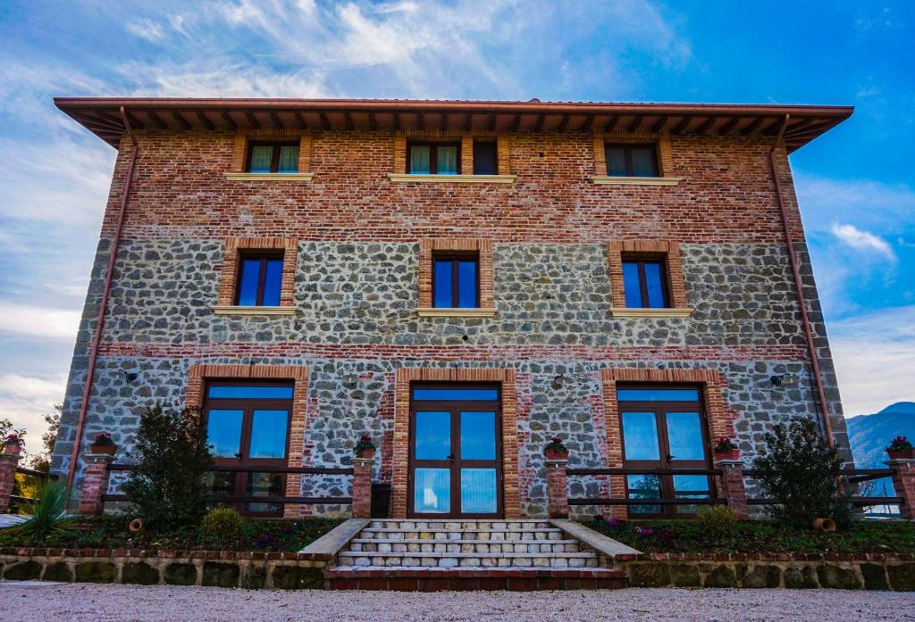 Un grand bâtiment en briques avec des escaliers se trouve à l'avant. dans l'établissement La Tenuta del Campo di Sopra, à Patrica