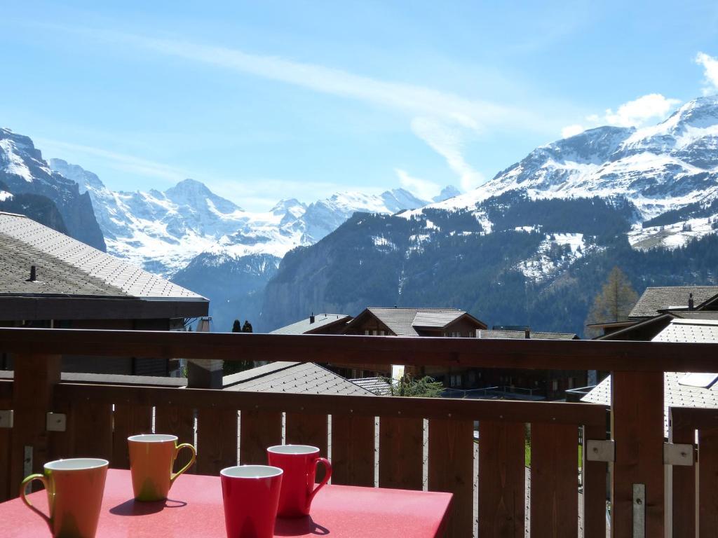 a table with coffee cups on a balcony with mountains at Chalet Bella Vista 6 in Wengen