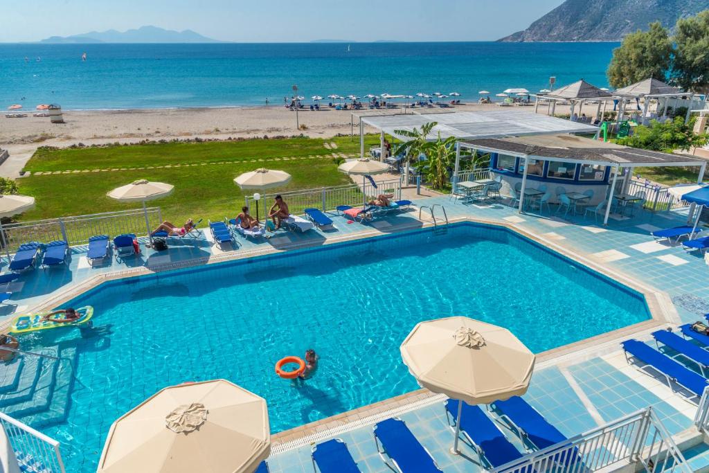 a pool with chairs and umbrellas and the beach at Kordistos Hotel in Kefalos