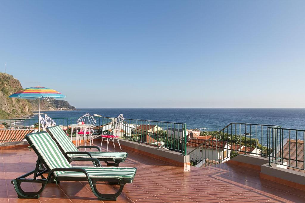 a patio with two chairs and an umbrella and the ocean at Casa Alto Santo António in Ponta do Sol