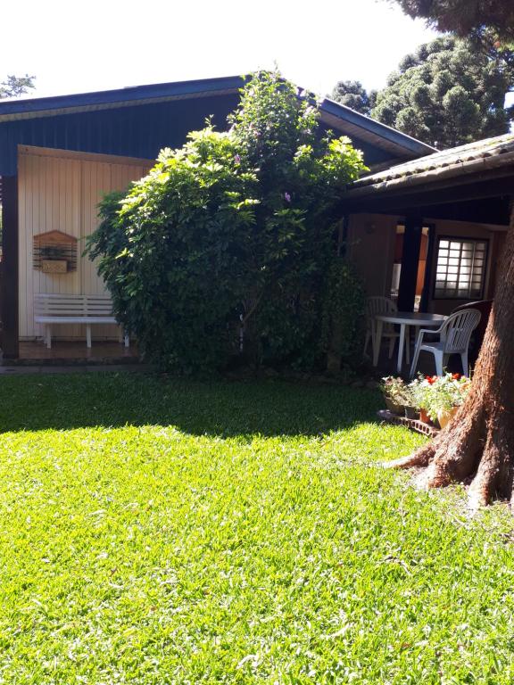 una casa con un banco y un árbol en el patio en Nossa casa em Canela, en Canela