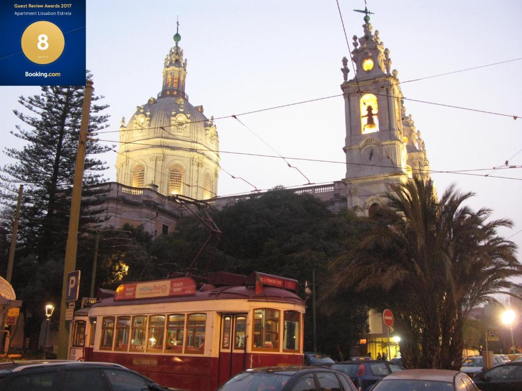 um carrinho em frente a um edifício com uma torre de relógio em Apartment Lissabon Estrela em Lisboa