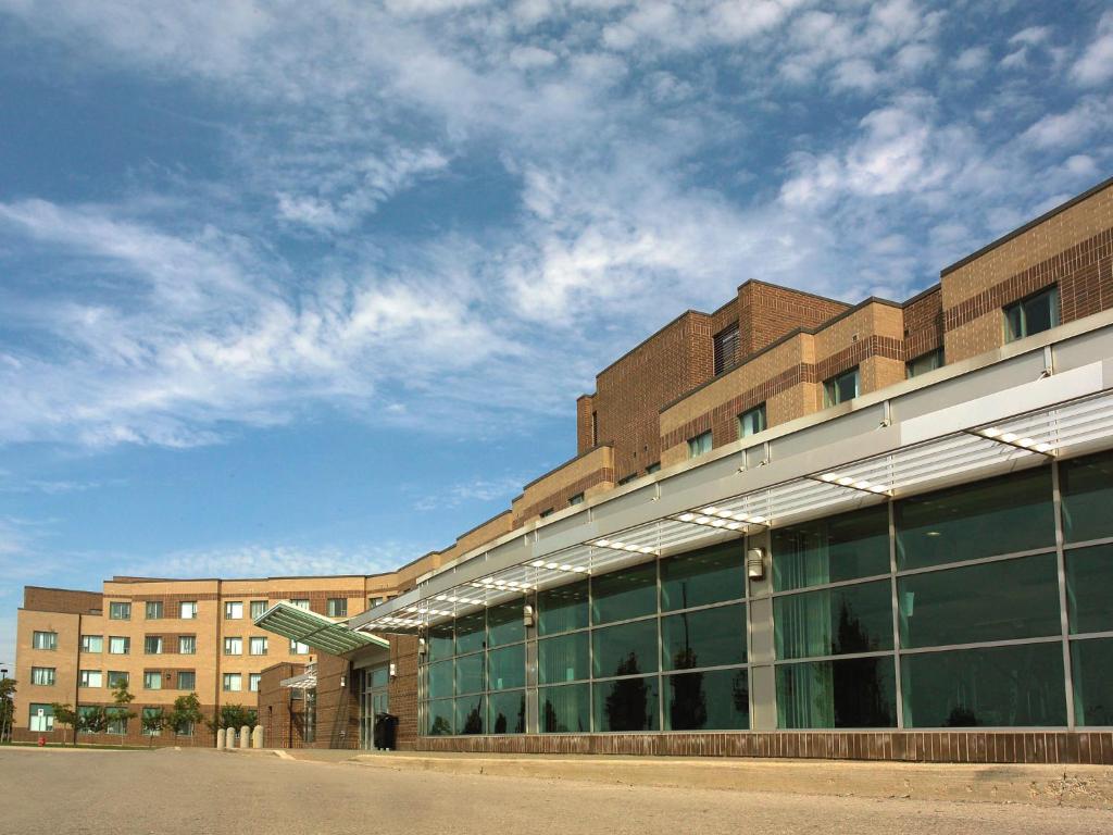 Residence & Conference Centre - Hamilton في هاميلتون: مبنى من الطوب مع نوافذ زجاجية على جانبه