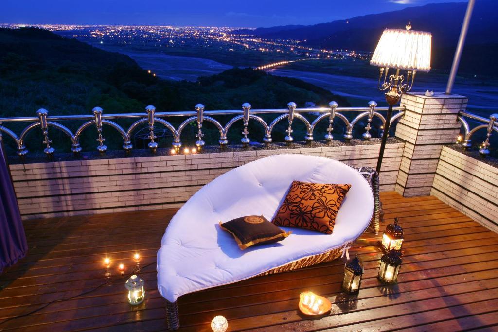 una silla blanca con 2 almohadas en un balcón con luces en Hao Wang Jiao House, en Datong