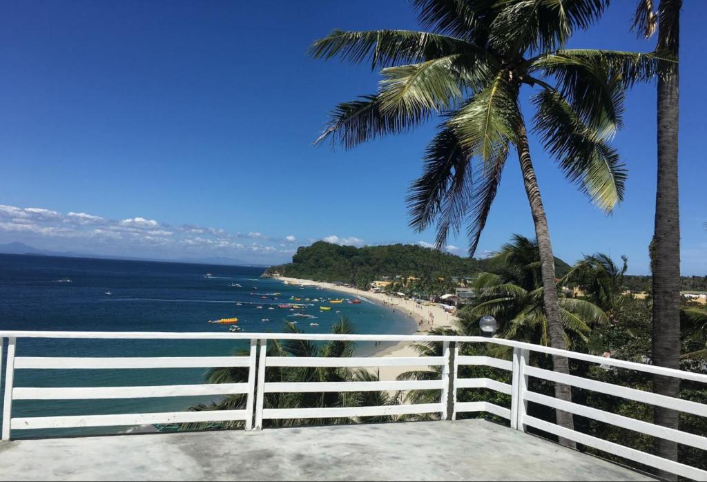 uma vista para uma praia com uma cerca branca e palmeiras em Playa Blanca Beach Resort em Puerto Galera