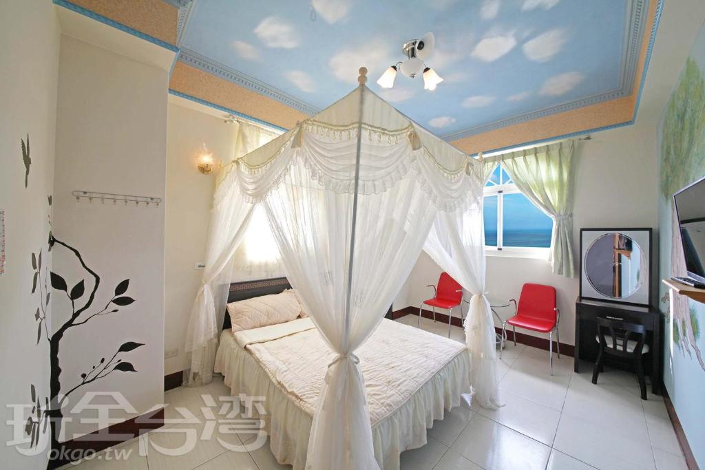 綠島鄉的住宿－綠島微風民宿 ，卧室配有白色天蓬床和窗户