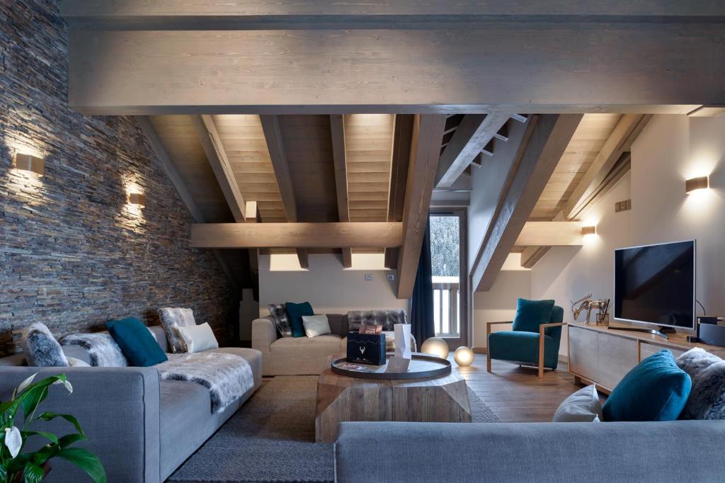 a living room with a couch and a tv at Le C by Alpine Residences in Courchevel