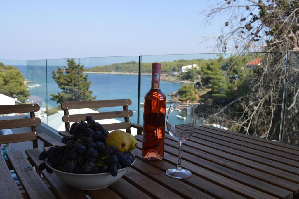 Summer House Krištof في Vrbanj: وعاء من الفاكهة وزجاجة من النبيذ على طاولة