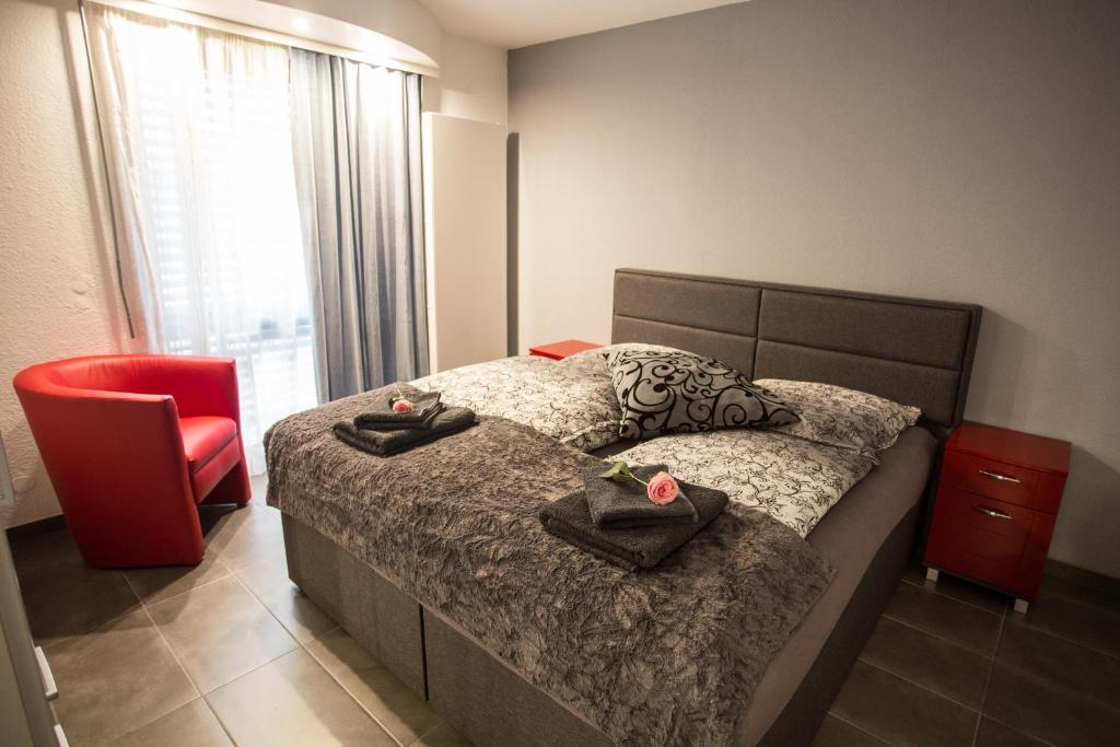 a bedroom with a bed and a red chair at Downtown Apartments in Baden-Baden