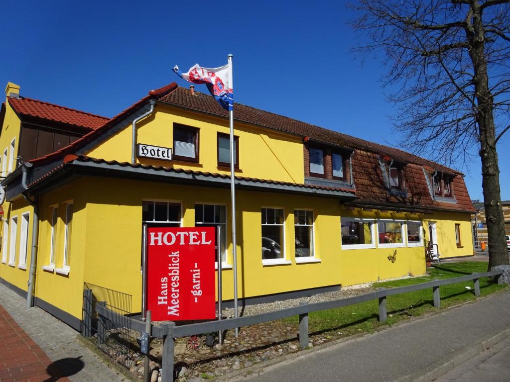 a yellow building with a hotel sign in front of it at Haus Meeresblick in Heiligenhafen