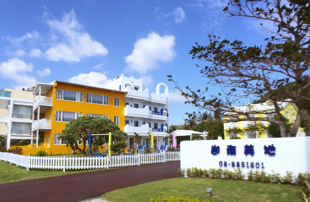 a yellow and white building with a white fence at Canaan B&amp;B Kenting in Eluan