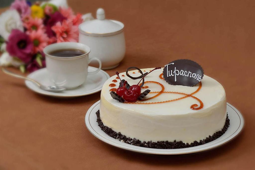 a cake on a table next to a cup of coffee at Apartments Tiraspol in Tiraspol