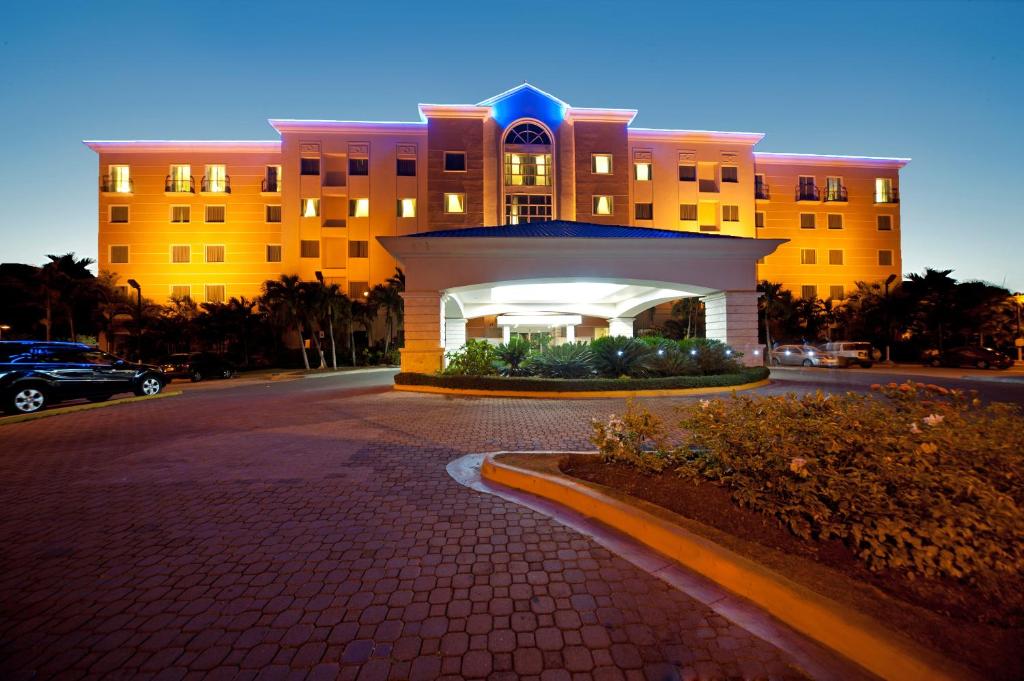 a large building with a circular driveway in front of it at Hodelpa Garden Court in Santiago de los Caballeros