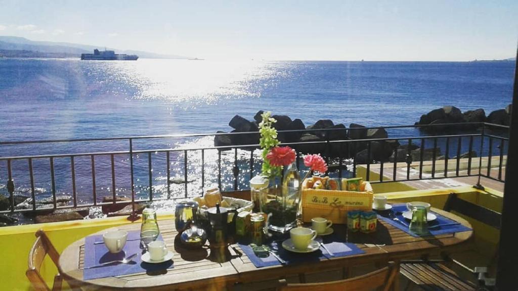una mesa en un balcón con vistas al océano en Casa Dei Saraceni, en SantʼAgata