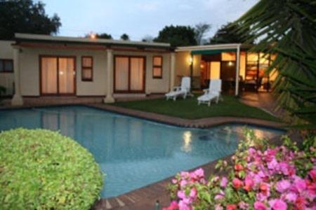 a house with a swimming pool with two lawn chairs at Somona Guest House in Johannesburg