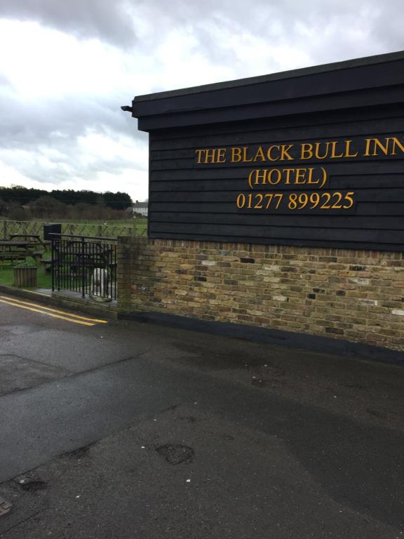 een zwart gebouw met een bord aan de zijkant bij The Black Bull Inn in Fyfield