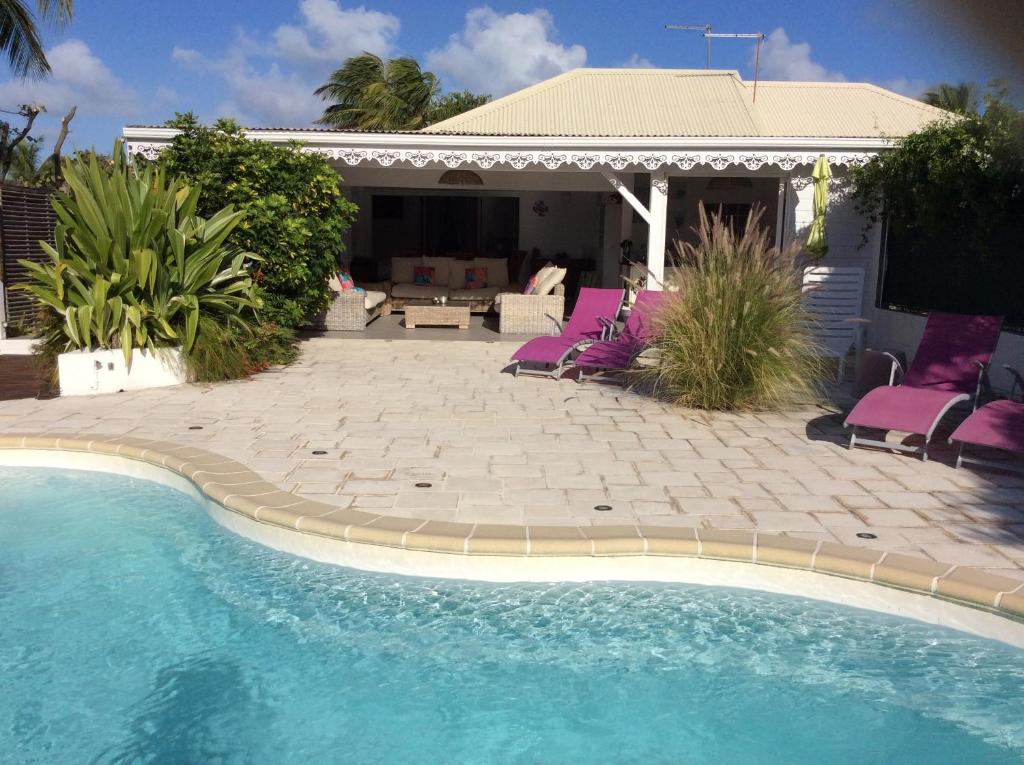 a swimming pool with purple chairs next to a house at Villa Acajou in Saint-François