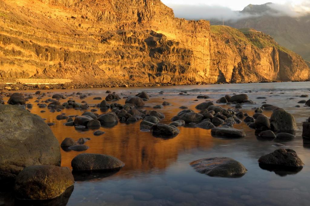 a group of rocks on a beach next to a mountain at Casa Lola in Agaete