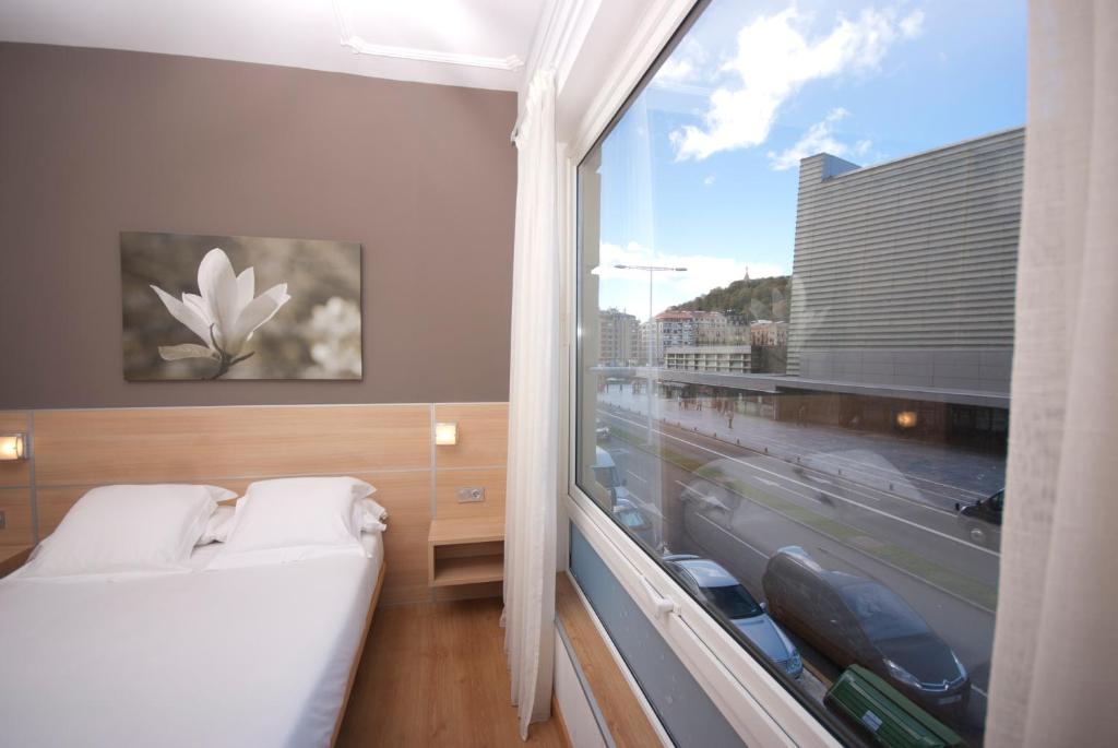 a bedroom with a bed and a large window at Pension Kursaal in San Sebastián