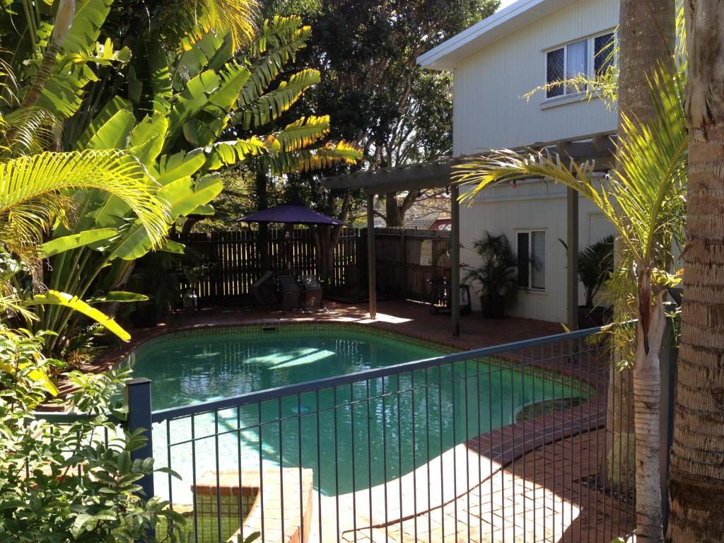 a swimming pool with a fence next to a house at Coconut Palms On The Bay in Hervey Bay