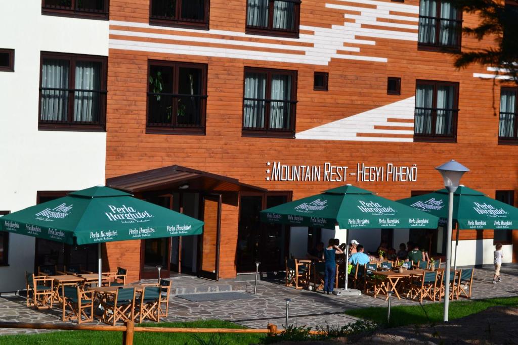 a building with tables and umbrellas in front of a building at Mountain-Rest Pension in Miercurea-Ciuc