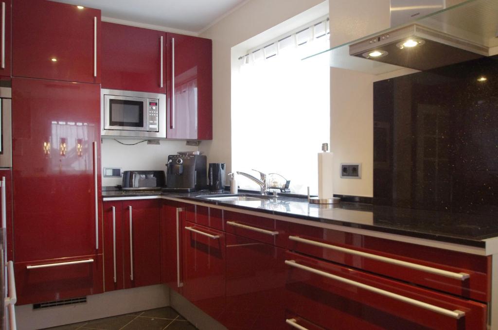 ボンにあるLuxury-Apartment Peterのキッチン(赤いキャビネット、黒いカウンタートップ付)