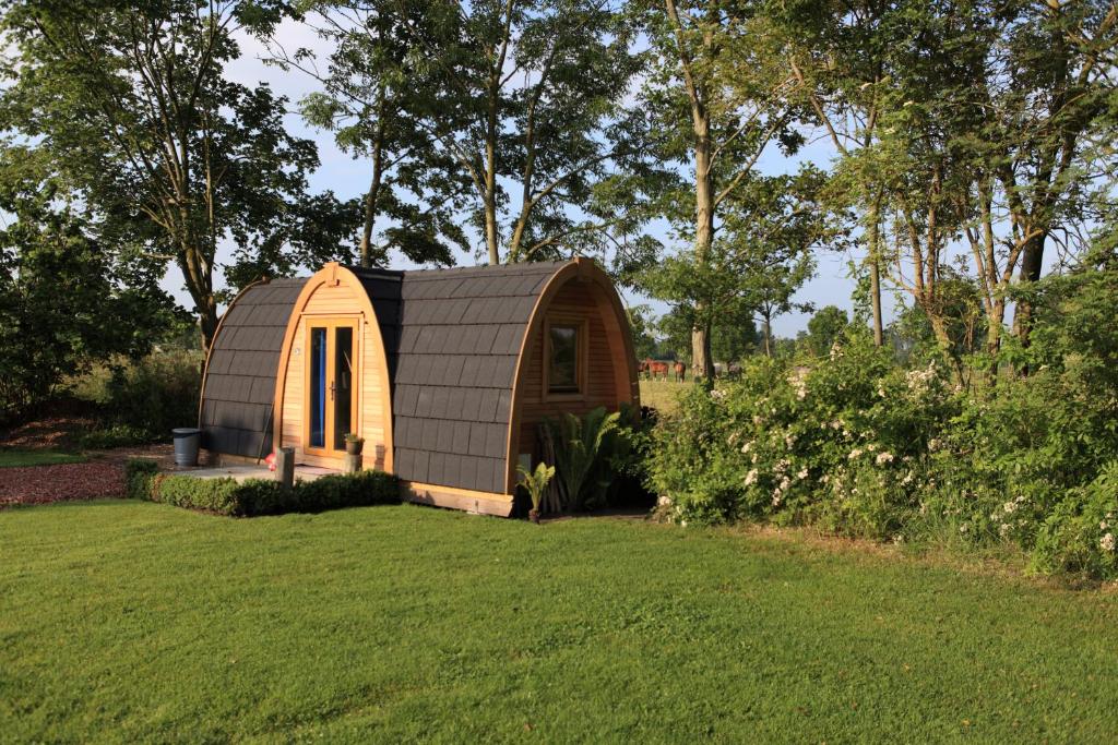 un petit hangar dans une cour avec une pelouse dans l'établissement Trekkershut, à Jubbega-Schurega