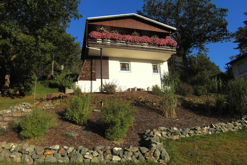 una casa con un balcón con flores rojas. en Ferienhaus im Ederbergland, en Hatzfeld