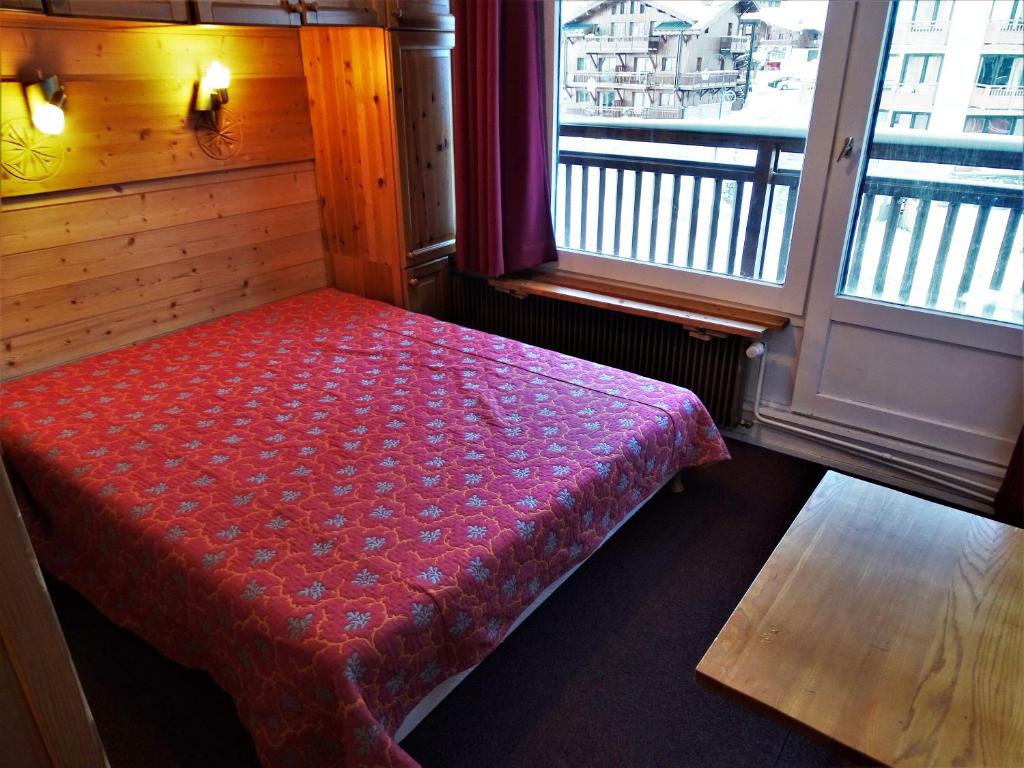 Cama roja en habitación con ventana en Appartements in Roc de Peclet by PiaundDirk, en Val Thorens