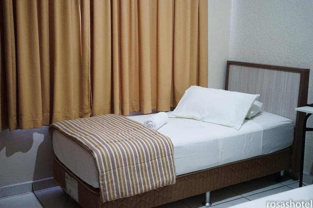 Bett in einem Zimmer mit einem Vorhang und einem Bettröckchen in der Unterkunft Rosa's Hotel in Toledo