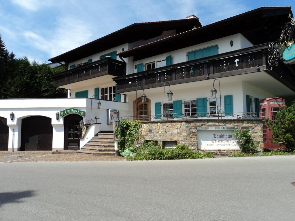 ein großes weißes Gebäude mit blauen Fenstern und einer Straße in der Unterkunft Landhaus Enzensberg in Füssen