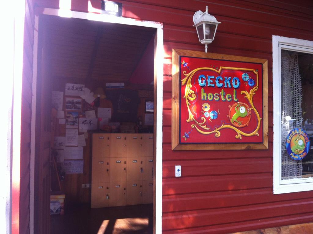 una casa roja con un cartel en el costado. en Gecko Hostel, en Pucón