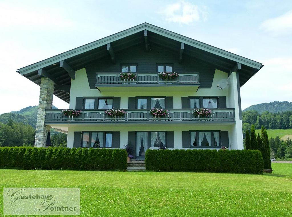 Großes Haus mit Balkon auf einer Wiese in der Unterkunft Gästehaus Pointner in Ruhpolding