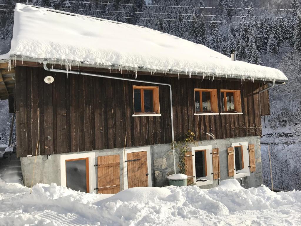 eine Holzhütte mit Schnee auf dem Dach in der Unterkunft 72 Route Du Fry in Les Gets