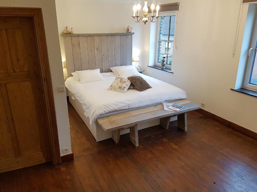 Schlafzimmer mit einem weißen Bett und Holzboden in der Unterkunft Widdingenhof in Wellen