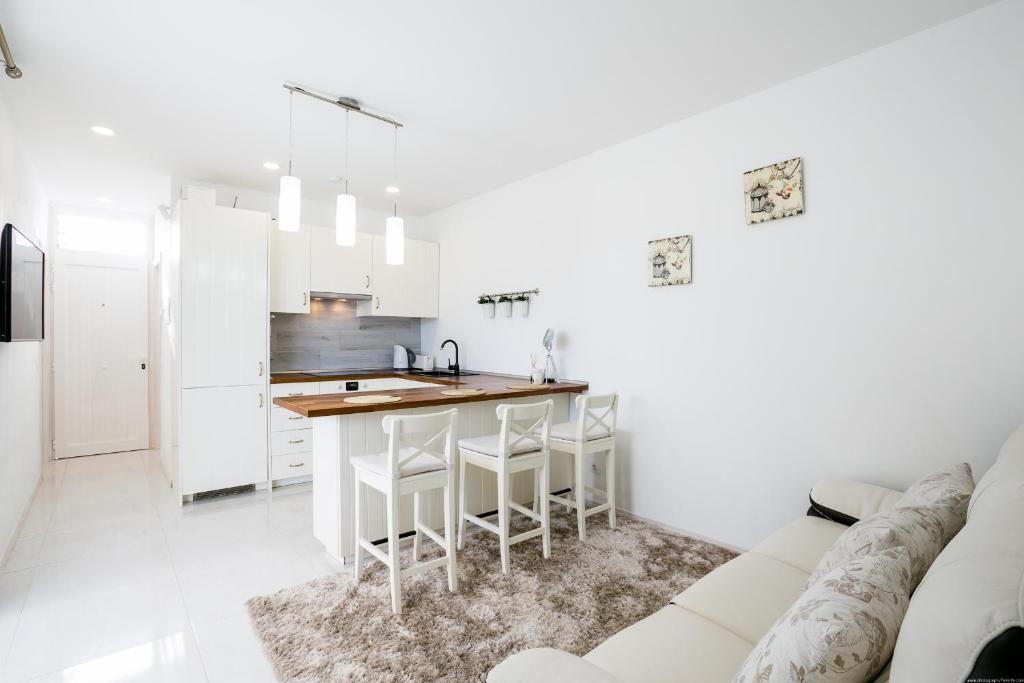 New Apartment In Tenerife في طوستا ديل سيلونثيو: مطبخ أبيض مع طاولة وأريكة بيضاء