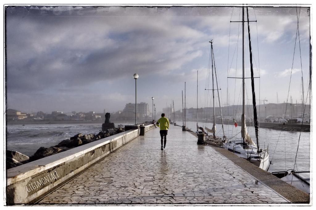 een man die over een pier loopt bij het water bij La Casa sul Molo in Viareggio