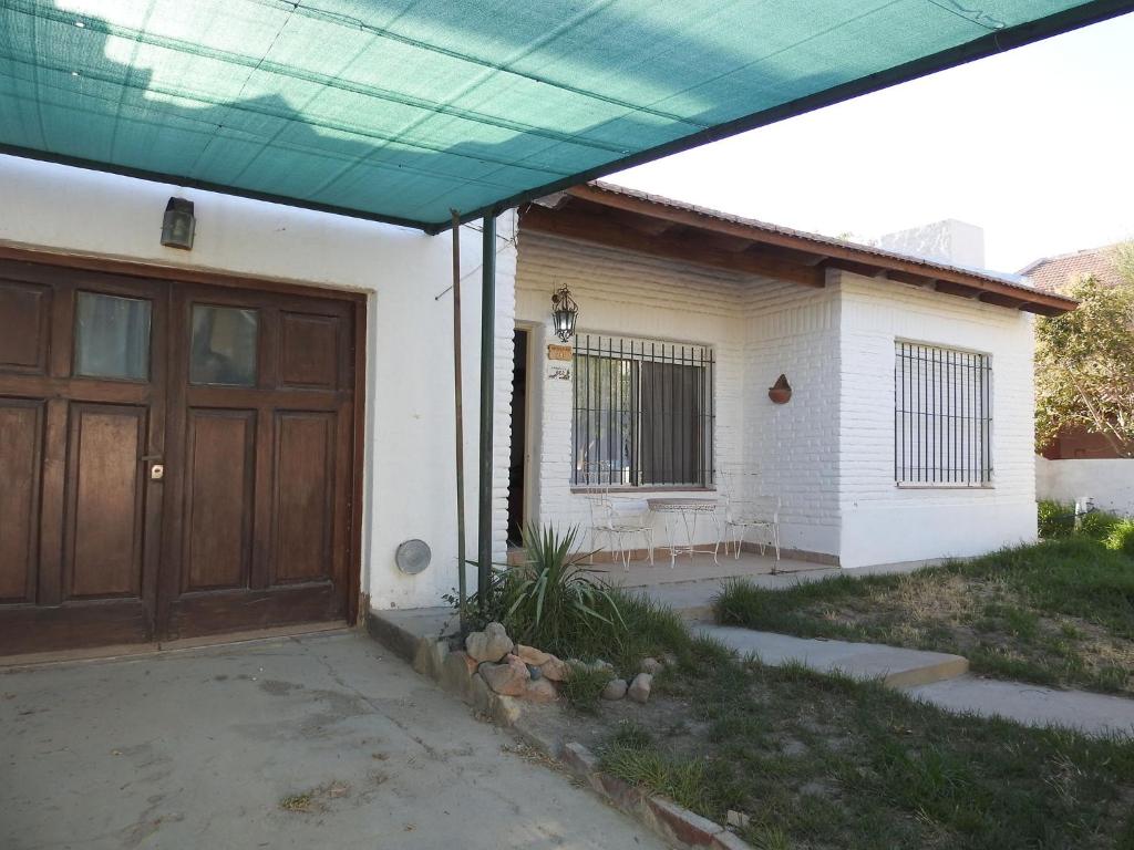 uma casa com uma porta de madeira e um alpendre em La Loberia - Las Grutas em Las Grutas