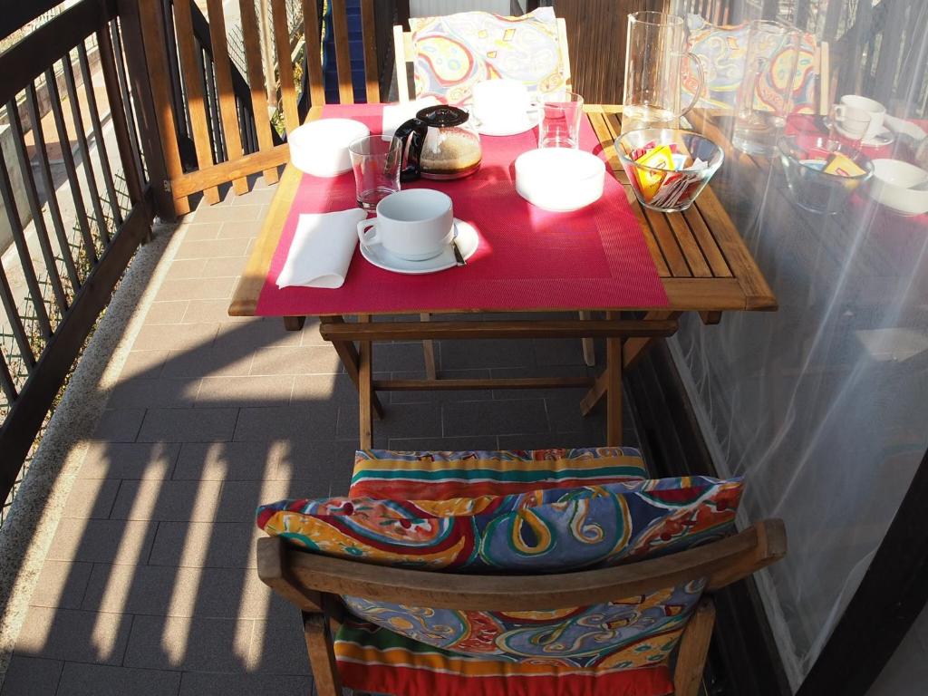 uma mesa de madeira numa varanda com uma toalha de mesa vermelha em Casa Vacanze Bungalow I Girasoli em Ventimiglia