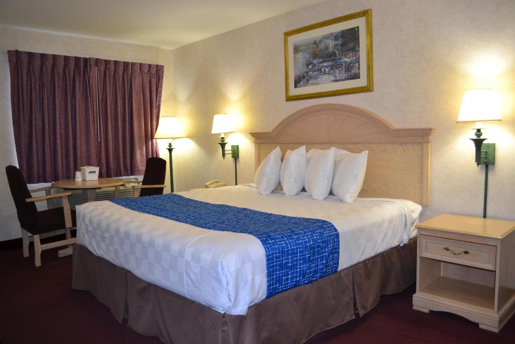 a hotel room with a large bed with a blue blanket at Travelodge by Wyndham Niagara Falls - New York in Niagara Falls