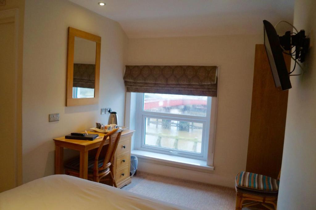 a bedroom with a bed and a desk and a window at The Arun View Inn in Littlehampton